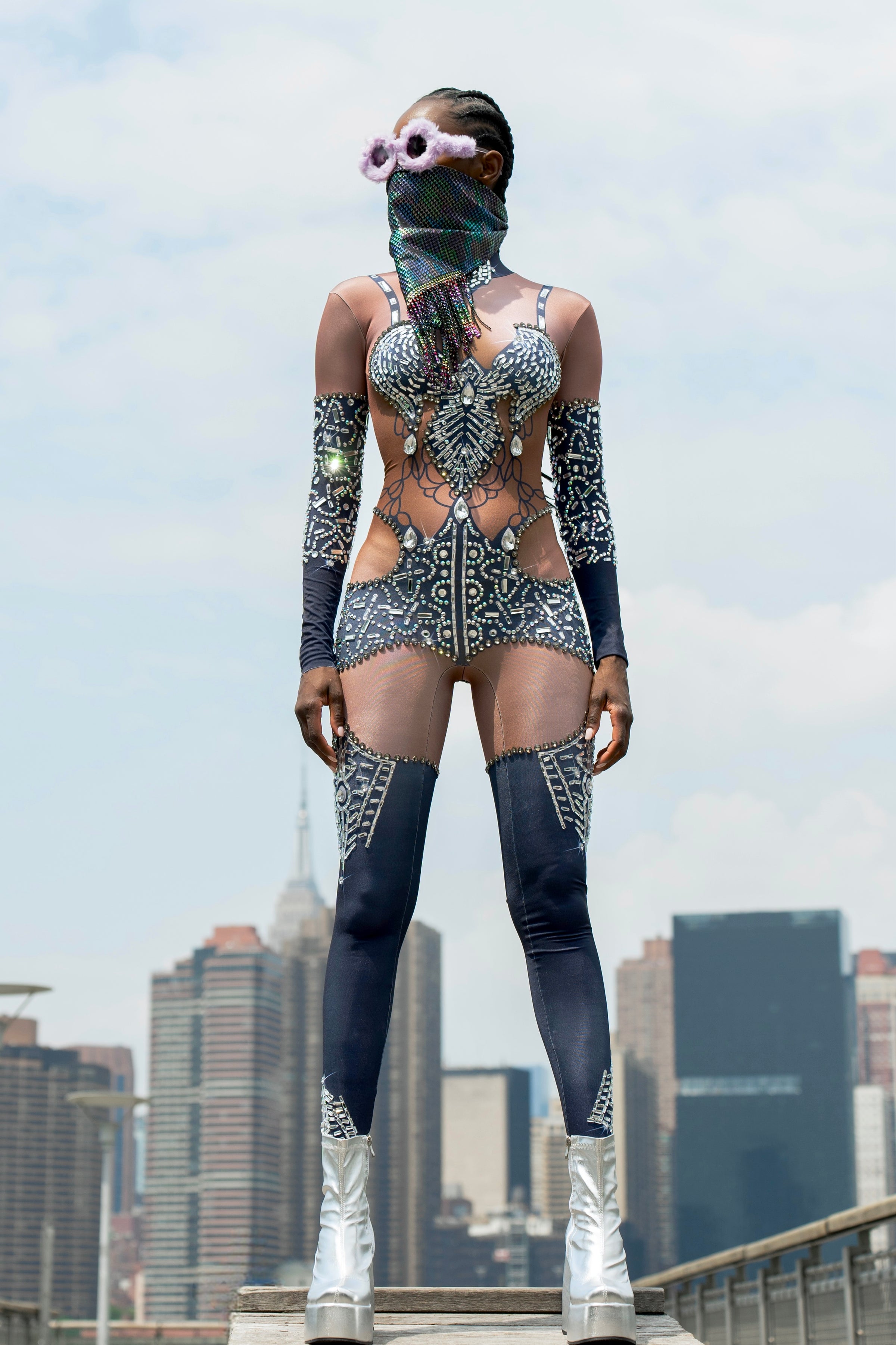 Bold festival bodysuit with rhinestones, sheer panels & leg warmers by HARMONIA NY, city skyline backdrop